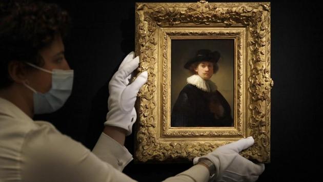 A Sotheby's employee adjusts a painting by Rembrandt Van Rijn called 'Self-portrait, wearing a ruff and black hat' at Sotheby's auction rooms in London. (AP Photo/Kirsty Wigglesworth)
