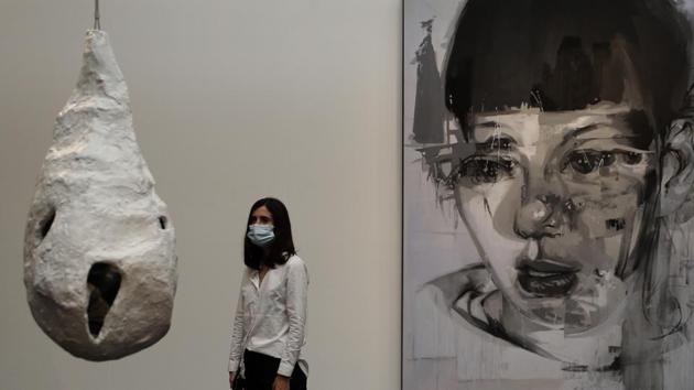 A woman looks at a sculpture by Louise Bourgeois called 'Fee Couturiere alongside a painting by Jenny Saville called 'Stare III' at Sotheby's auction rooms in London. (AP Photo/Kirsty Wigglesworth)