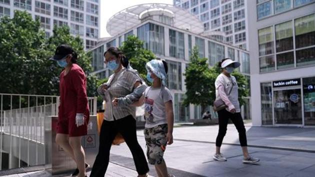 People wearing face masks walk past an office and commercial complex in Beijing's Central Business District (CBD). (REUTERS)