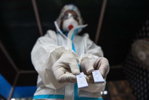 A health worker wearing PPE coveralls holds out Rapid Antigen test kits before preparing to collect swab samples to test for coronavirus, near Minto Bridge in New Delhi. (Sanchit Khanna/HT PHOTO) A health worker wearing PPE coveralls holds out Rapid Antigen test kits before preparing to collect swab samples to test for coronavirus, near Minto Bridge in New Delhi. (Sanchit Khanna/HT PHOTO)