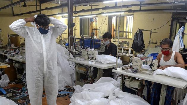 A supervisor inspects finished Personal Protective Equipment (PPE) products at a garment manufacturing unit in Mumbai on July 24. Amid other preparations, India has also managed to produce 20.2 million PPE kits after the government had placed orders in March to equip the medical workers for the coronavirus fight, HT reported on July 23. (Indranil Mukherjee / AFP)