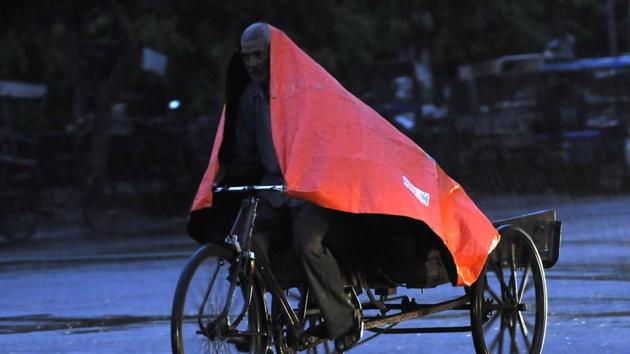 A man uses a plastic sheet for cover against the rain, at Sector 19, in Noida. (Sunil Ghosh / Hindustan Times) A man uses a plastic sheet for cover against the rain, at Sector 19, in Noida. (Sunil Ghosh / Hindustan Times)