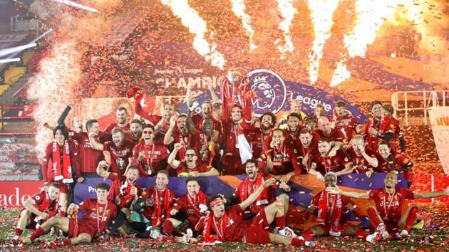 Liverpool's Jordan Henderson, teammates and staff celebrate with the trophy after winning the Premier League.(Pool via REUTERS)