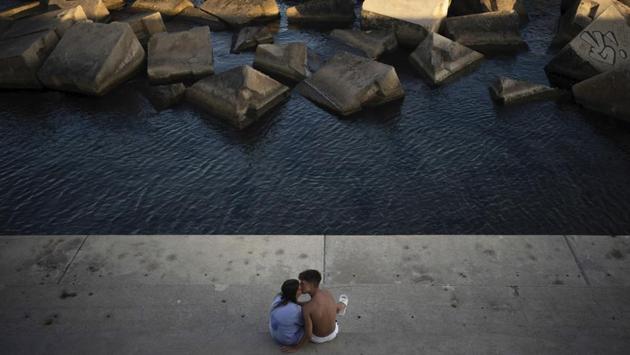A couple kisses as they sit by the sea in Barcelona on July 25. Countries around the Mediterranean Sea were banking on a glimpse of tourism to get economies through the summer before the cold snap drives people indoors and ushers in a second chapter to the pandemic. Now, it appears the virus may not wait for the winter months. (Felipe Dana / AP) 