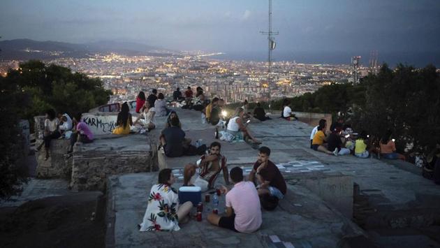 People gather outdoors at dusk on a viewpoint in Barcelona on July 25. While families and the at-risk elderly are mostly complying with rules to wear face masks and maintain a 1.5 metre distance from others, teenagers and young adults in many of Spain’s cities have been completely flouting the health rules and guidelines, AP reports. (Felipe Dana / AP) 