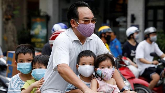 A man and his children, all wearing protective masks, ride a bicycle on a street during the coronavirus disease (Covid-19) outbreak, in Hanoi, Vietnam. (REUTERS) A man and his children, all wearing protective masks, ride a bicycle on a street during the coronavirus disease (Covid-19) outbreak, in Hanoi, Vietnam. (REUTERS)
