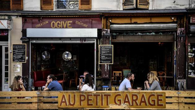People have drinks behind a wooden enclosure at a cafe in Paris on July 22. With the general scientific consensus that it is much harder to catch the virus outdoors than inside, cafe-goers are more at ease on the street in the summer, AFP reported. (Christophe Archambault / AFP)
