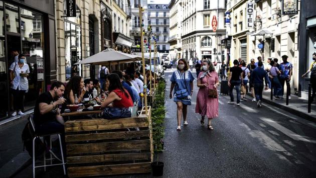 People walk past an extended terrace of a restaurant made of wooden pallets in Paris on July 23. Paris Mayor Anne Hidalgo has eased outdoor seating limits so owners can lure virus-wary clients, and has also commandeered hundreds of parking spots for additional seating. (Christophe Archambault / AFP)