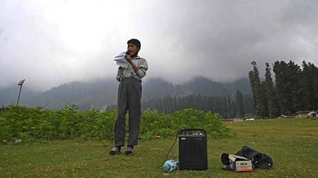 A student speaks on a loudspeaker during a class at an open-air school in Doodhpathri on July 27. Unable to afford smartphones, and with limited internet access in remote villages, many students have been unable to attend online lessons. (Tauseef Mustafa / AFP)