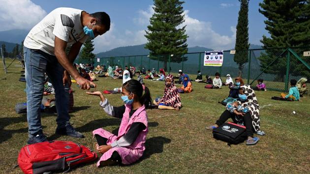 A teacher dispenses hand sanitiser to a student at their open-air school in Doodhpathri on July 28. At the school, pupils from 15 villages are supplied with face masks and sanitiser before sitting in eight groups divided by age. Teachers carry whiteboards to the meadow to use during the three- to four-hour classes. “It felt wrong to receive my salary sitting at home,” teacher Manzoor Ahmad told AFP. (Tauseef Mustafa / AFP)