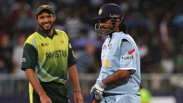 MS Dhoni of India leaves the field as rain stops play with Shahid Afridi of Pakistan looking on(Getty Images)