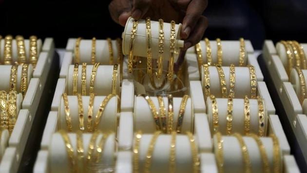 A salesman arranges gold bangles inside a jewellery showroom in Mumbai in this file photo. Gold rose above <span class='webrupee'>?</span>52,000 per 10 gram on Tuesday, extending gains to the third day, in Indian markets.(Reuters Photo)