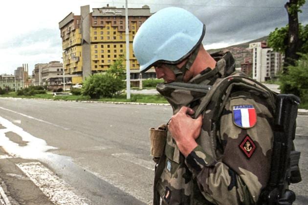 FILE - In this Sunday May 14, 1995 file photo, a French UN peacekeeper stands by his anti-sniper position backdropped by the Holiday Inn hotel on Sarajevo's Sniper Alley. The Holiday Hotel, which opened as Holiday Inn, a luxurious accommodation for world's royalty, film stars and other dignitaries who came to watch the 1984 Winter Olympics, and less than a decade later, became ground zero of the bloody siege of Sarajevo in the 1990's. (AP)