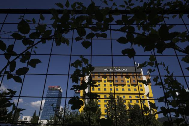The Holiday Hotel, which opened as Holiday Inn, a luxurious accommodation for world's royalty, film stars and other dignitaries who came to watch the 1984 Winter Olympics, and less than a decade later, became ground zero of the bloody siege of Sarajevo in the 1990's, is seen through a fence in Sarajevo, Bosnia, Wednesday, July 29, 2020. The bright yellow Holiday Hotel in downtown Sarajevo, a famous symbol of survival of the Bosnian capital, has seen good and bad times in its turbulent history, but now the landmark's survival is in more danger than ever, with the coronavirus pandemic leaving it with only a few occasional guests. (AP Photo/Kemal Softic) (AP)