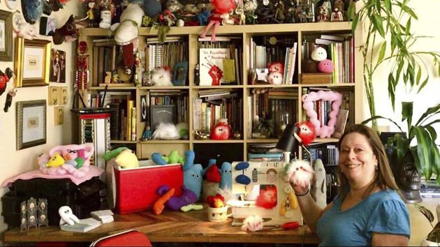 This July 25, 2020 photo shows Amy Micallef posing with her craft creations at her home. While Broadway stages remain dark due to the pandemic, Broadway workers are concentrating on side hustles. Micallef, a Broadway seamstress who has worked in the wardrobe departments of “Hamilton,” “Waitress” and “Frozen,” makes gleeful representations of COVID-19 for sale, complete with a pair of eyes and faux fur. (AP) This July 25, 2020 photo shows Amy Micallef posing with her craft creations at her home. While Broadway stages remain dark due to the pandemic, Broadway workers are concentrating on side hustles. Micallef, a Broadway seamstress who has worked in the wardrobe departments of “Hamilton,” “Waitress” and “Frozen,” makes gleeful representations of COVID-19 for sale, complete with a pair of eyes and faux fur. (AP)