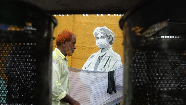 A man walks in front of a graffiti honoring those on the frontlines in the fight against the coronavirus outside a train station as dust bins are seen in foreground in Mumbai.(AP) A man walks in front of a graffiti honoring those on the frontlines in the fight against the coronavirus outside a train station as dust bins are seen in foreground in Mumbai.(AP)