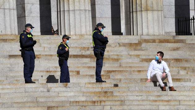 Protective Services officers speak to a man sitting on the steps of the Shrine of Remembrance in Melbourne on July 31. The Australian government has now extended some of Melbourne’s lockdown measures to surrounding cities, and deployed disaster-relief teams to elderly-care centres. (William West / AFP) Protective Services officers speak to a man sitting on the steps of the Shrine of Remembrance in Melbourne on July 31. The Australian government has now extended some of Melbourne’s lockdown measures to surrounding cities, and deployed disaster-relief teams to elderly-care centres. (William West / AFP)