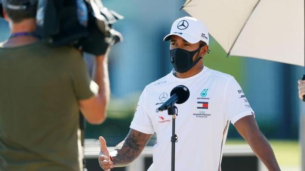 Mercedes' Lewis Hamilton talks to the media as he wears a protective face mask in the paddock ahead of the British Grand Prix.(REUTERS)