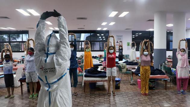 A health worker wearing personal protective equipment (PPE) gives yoga instructions to patients at a Covid-19 Care Center in New Delhi on July 30. The rate of recoveries has also increased in the country. The number of recovered patients crossed the one million mark on June 30 and is now 1.9 times the total active cases. (T. Narayan / Bloomberg)