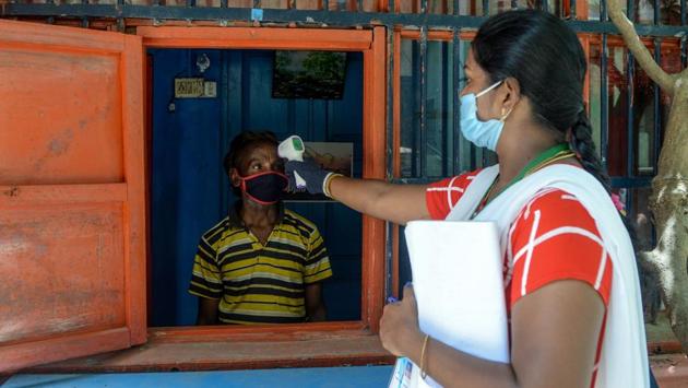 A health worker (R) checks the body temperature of a man at a containment zone in Chennai on July 30. The journey to a million recoveries took 150 days since March 2, but each additional quarter of that million has come at a faster pace. While the first 250,000 recoveries came in 114 days, successive quarters took only 17, 11 days and 8 days respectively. (Arun Sankar / AFP)