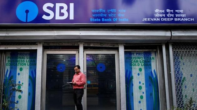 A man checks his mobile phones in front of State Bank of India (SBI) branch in Kolkata, India.(REUTERS) A man checks his mobile phones in front of State Bank of India (SBI) branch in Kolkata, India.(REUTERS)
