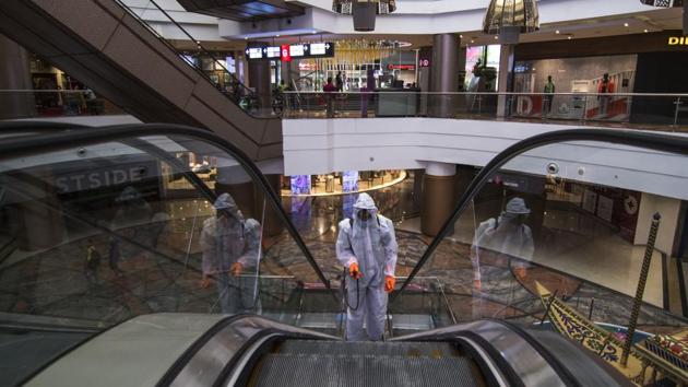 A man in personal protective equipment(PPE) sprays disinfectant inside a shopping mall premises as part of an Unlock 3 reopening in Mumbai on July 30. 64.5% of all Covid-19 patients have now recovered across India as the country moves towards the third stage of its graded unlocking from August 1. This is higher than the global average of 61.9%. (Pratik Chorge / HT Photo)