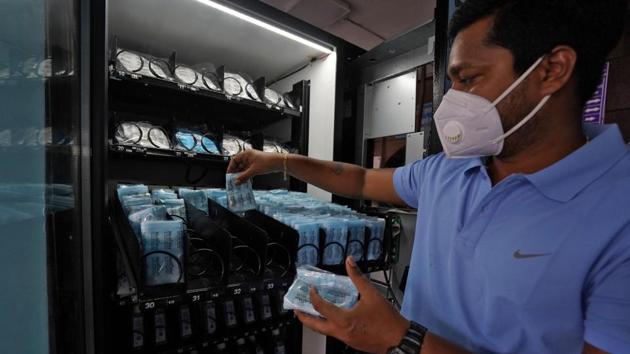 A worker wearing a protective face mask fills a vending machine selling protective face masks and gloves at Dadar railway station in Mumbai on July 31. Addressing a press briefing, Officer on Special Duty in the Health Ministry Rajesh Bhushan said on July 30 that the ‘test, track and treat’ strategy has shown good results in terms of managing the situation by curbing the spread of infections and keeping the mortality low. (Hemanshi Kamani / REUTERS)