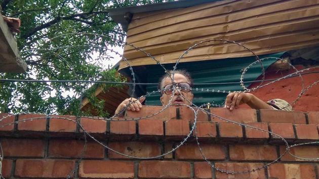 Congress leader and former Union minister Saifuddin Soz climbs up the wall of his house to speak to a media person, in Srinagar.(PTI)