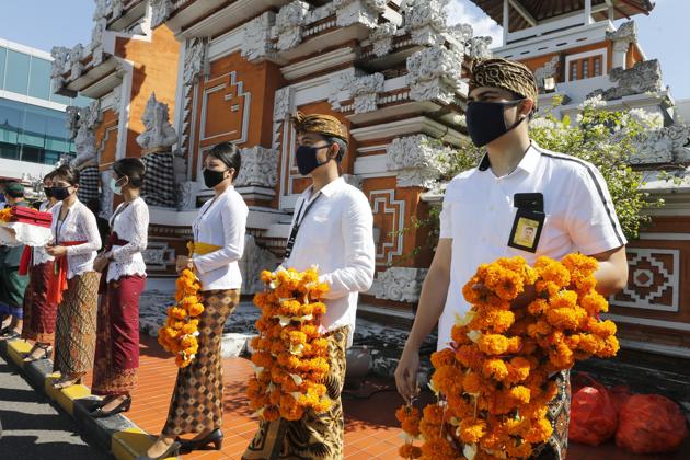 Airport officers wearing face masks line up as they hold flowers to welcome passengers at Bali airport, Indonesia on Friday, July 31, 2020. Indonesia's resort island of Bali reopened for domestic tourists after months of lockdown due to a new coronavirus.(AP) Airport officers wearing face masks line up as they hold flowers to welcome passengers at Bali airport, Indonesia on Friday, July 31, 2020. Indonesia's resort island of Bali reopened for domestic tourists after months of lockdown due to a new coronavirus.(AP)