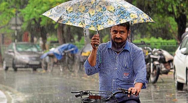 A man balances an umbrella while cycling in the rain in Mohali on Saturday. (GURMINDER SINGH/HT) A man balances an umbrella while cycling in the rain in Mohali on Saturday. (GURMINDER SINGH/HT)