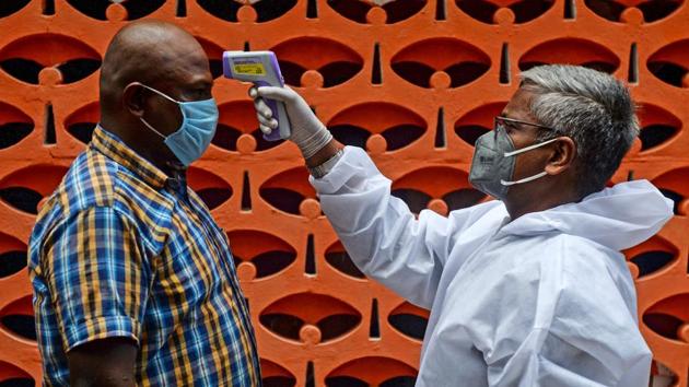 A health worker thermal screens a resident at a containment zone in Chennai on July 30. However, the guidelines also regulated that a strict lockdown will continue in containment zones – areas that report clusters of the disease – till August 31 and asked authorities to maintain strict perimeter control in such zones. (Arun Sankar / AFP)