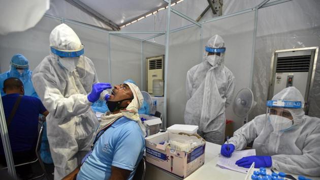 A health worker in PPE overalls collects swab sample to test for Covid-19 at the Indo-Israel Non-Invasive Rapid Covid-19 test study camp, at Dr Ram Manohar Lohia Hospital in New Delhi on July 31. More than a million cases were added to the country’s infection tally in July—from 585,493 on July 1 to 1,638,870 on July 31—and the death toll went up to 35,747 from 17,400 in the same period, HT reported. (Biplov Bhuyan / HT Photo)