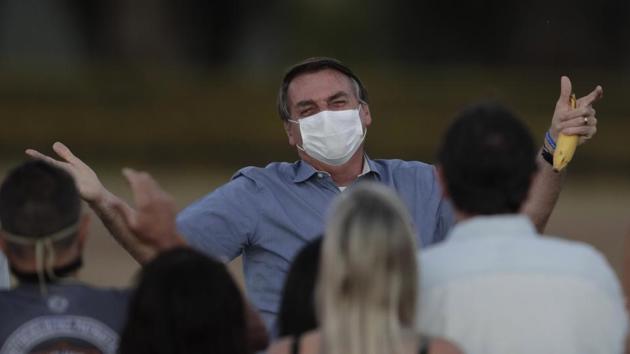 Brazil's President Jair Bolsonaro, who is infected with Covid-19, wears a protective face mask as he talks with supporters during a Brazilian flag retreat ceremony outside his official residence the Alvorada Palace, in Brasilia, Brazil.(AP)