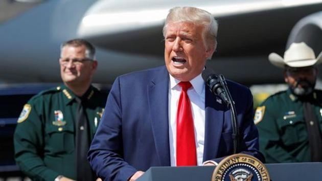 US President Donald Trump speaks to a crowd of supporters, flanked by a line of local law enforcement, as he arrives at Tampa International Airport, in Tampa, Florida, US.(REUTERS)
