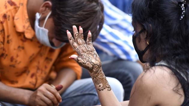 A woman has henna (mehendi) applied to her forearms on the eve of Rakshabandhan festival at Sadar Bazar, in Gurugram, India, on Sunday, August 02, 2020. (Parveen Kumar/Hindustan Times)