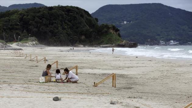 Beach goers stay within a roped off grid in Shimoda on July 30. “The government should have had a proper strategy to contain the transmission as promptly as possible,” Kenji Shibuya, a professor at King’s College London and a former chief of health policy at the World Health Organization told Bloomberg. “Japan is making things worse by just waiting and seeing.” (Kiichiro Sato / AP) Beach goers stay within a roped off grid in Shimoda on July 30. “The government should have had a proper strategy to contain the transmission as promptly as possible,” Kenji Shibuya, a professor at King’s College London and a former chief of health policy at the World Health Organization told Bloomberg. “Japan is making things worse by just waiting and seeing.” (Kiichiro Sato / AP)