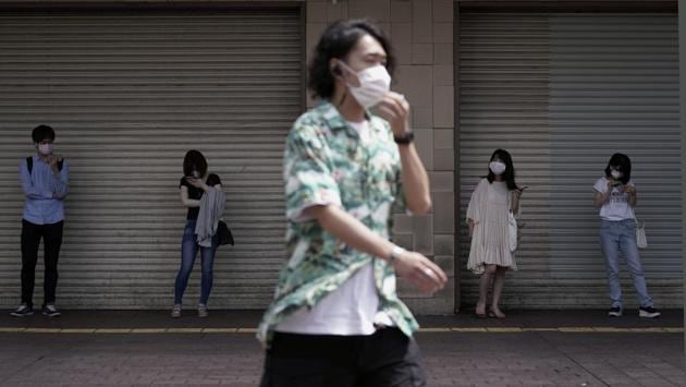 People wearing masks maintain social distance while hanging out near Shibuya pedestrian crossing in Tokyo on July 31. While people have continued to wear masks throughout the pandemic, the current infections have largely occurred in situations where face coverings aren’t typically worn, like group dining and drinking events. (Eugene Hoshiko / AP) People wearing masks maintain social distance while hanging out near Shibuya pedestrian crossing in Tokyo on July 31. While people have continued to wear masks throughout the pandemic, the current infections have largely occurred in situations where face coverings aren’t typically worn, like group dining and drinking events. (Eugene Hoshiko / AP)