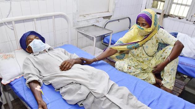 A family member next to a patient who is undergoing treatment after allegedly drinking spurious alcohol, at Civil hospital in Tarn Taran, Punjab. (Photo by Sameer Sehgal/ Hindustan Times)