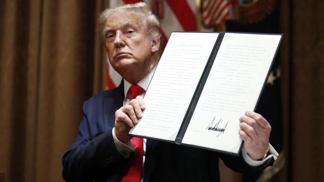 President Donald Trump holds up a signed Executive Order on hiring American workers, during a meeting with U.S. tech workers, in the Cabinet Room of the White House, Monday, Aug. 3, 2020, in Washington.(AP photo)