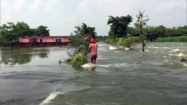 A man wades through flooded water following a rise in the water level of Burhi Gandak River due to rainfall, in Muzaffarpur on Sunday.(ANI Photo)