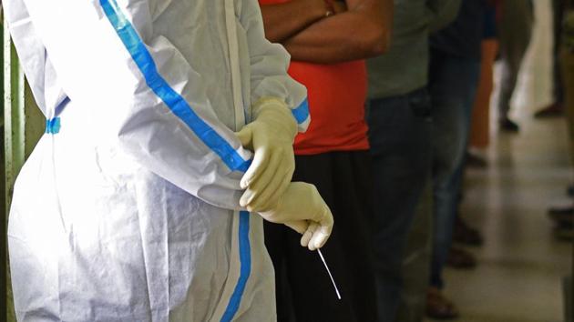A Kolkata Municipal Corporation (KMC) health worker pictured with a swab for sample collection while people wait on July 31. The health ministry on August 3 said that the country’s drugs authorities had allowed Serum Institute of India, the world’s largest manufacturer of vaccines by volume, to conduct phase 2 and 3 trials of a vaccine candidate developed by Oxford University and AstraZeneca Plc. (Samir Jana / HT Photo)