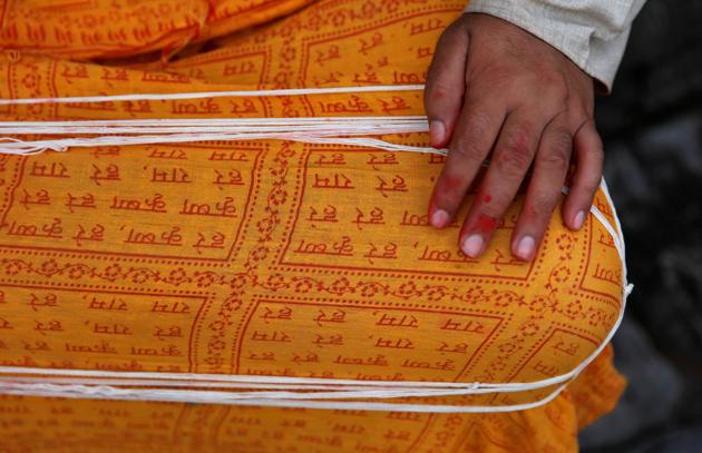 A Hindu priest puts sacred threads on his lap as he waits for devotees during the Janai Purnima festival (Sacred Thread Festival) at Pashupatinath Temple in Kathmandu, Nepal, August 3, 2020. (REUTERS)