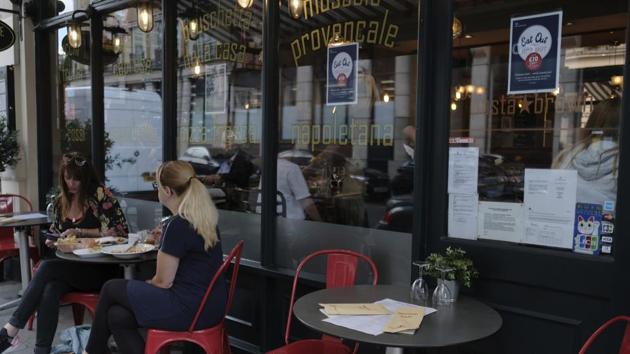 Customers eat at restaurant next to signs indicating discounts off food, in central London. (AP) Customers eat at restaurant next to signs indicating discounts off food, in central London. (AP)