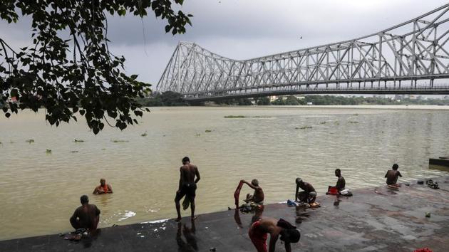 People take bath on the bank of Hooghly River beside Howrah Bridge during West Bengal state lockdown to prevent the spread of coronavirus in Kolkata.(AP)
