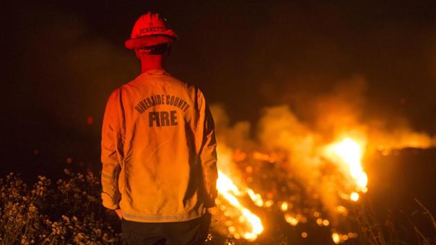 A firefighter watches a brush fire at Banning in California on August 1. A wildfire in mountains east of Los Angeles that has forced thousands of people from their homes was sparked by a malfunctioning diesel vehicle, fire officials told AP on August 3. (Ringo H.W. Chiu / AP)