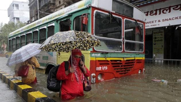 Commuters wade through a water logged street, following heavy rain in Mumbai on August 4. Several areas in the city and suburbs have received more than 200 mm rainfall since August 3 night, which brought life to a juddering halt and disrupted rail and road traffic on August 4. (Rajanish Kakade / AP)