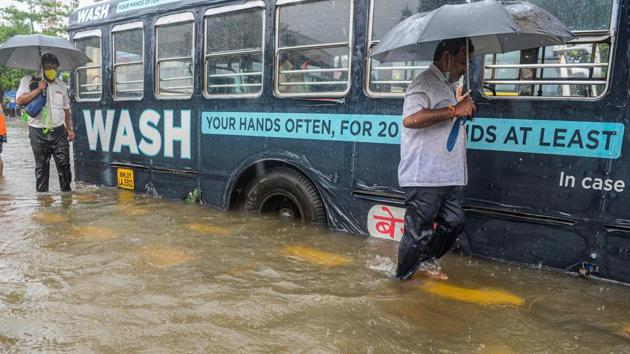 Commuters wade past a stranded bus on a flooded road on August 4. Water logging outside the Nair Hospital in central Mumbai, where several Covid-19 patients from the city are being treated, posed a problem for its medical staff. “Nurses and other medical staff have been struggling to reach the hospital due to water-logging in the premises and elsewhere, a resident doctor from the hospital told PTI. (Indranil Mukherjee / AFP)
