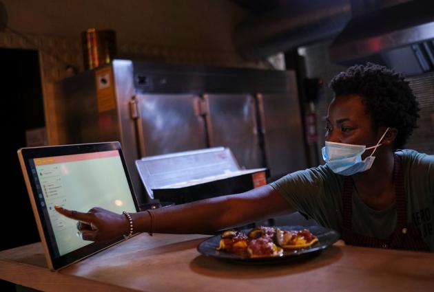 An employee using the "Funky Pay" app informs clients that their order is ready, at Funky Pizza restaurant, where the app replaces waiters, in Palafrugell, near Girona, Costa Brava, Spain July 31, 2020. (REUTERS)