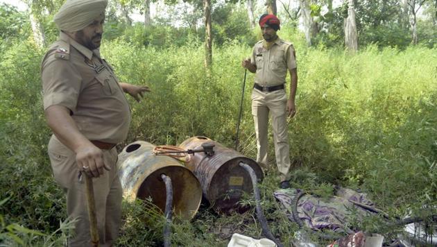 Police personnel with recovered stills near Sutlej river in Ludhiana on Tuesday. (Gurpreet Singh/HT) Police personnel with recovered stills near Sutlej river in Ludhiana on Tuesday. (Gurpreet Singh/HT)