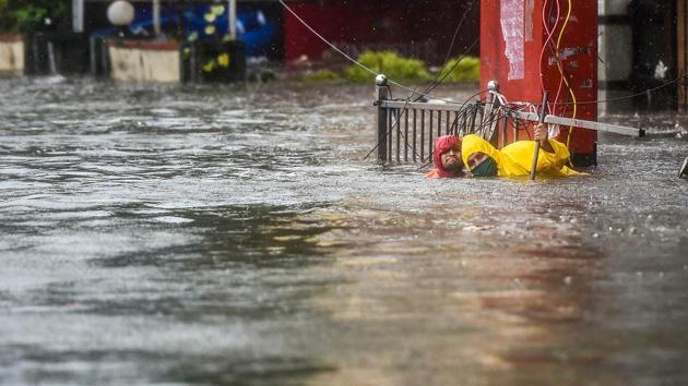 Workers clean a manhole in a water logged area following heavy rain at Sion in Mumbai on August 4. A 35-year-old woman and her two children were swept away in a swollen drain after their house collapsed due to heavy rainfall in Santacruz on August 4 afternoon. (Kunal Patil / PTI)
